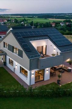 an aerial view of a modern house with solar panels on the roof and patio area