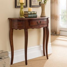 a wooden table with two vases on top of it next to a lamp and pictures