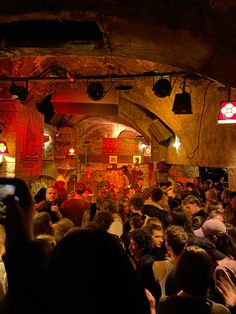 a large group of people in a room with lights on and one person holding up a cell phone