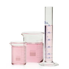 three beakles and measuring cups are shown on a white surface, one is pink