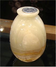 a white vase sitting on top of a black table next to a window sill