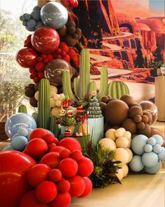 an assortment of balloons and other decorations on display in a room with large pictures behind them