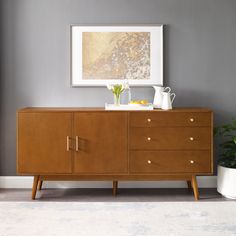 a wooden cabinet with two vases on top of it next to a potted plant