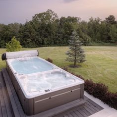 a hot tub sitting on top of a wooden deck next to a lush green field