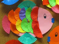 colorful paper plates with fish on them sitting on the floor in front of other decorations