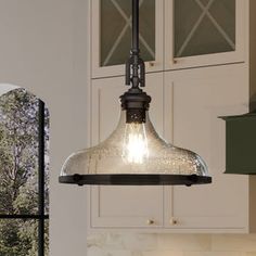 a kitchen light hanging from the ceiling over a counter top with cabinets in the background