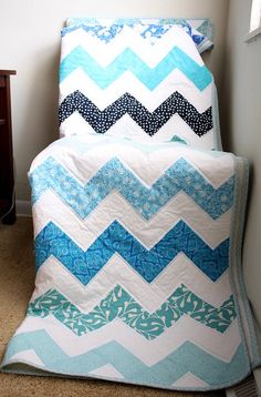 a blue and white quilt sitting on top of a bed next to a night stand