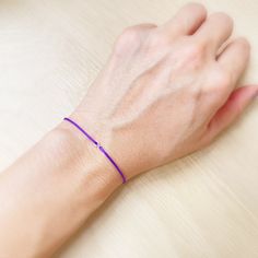 a person wearing a purple bracelet on their wrist