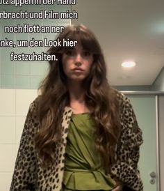 a woman with long hair standing in front of a mirror wearing a leopard print jacket