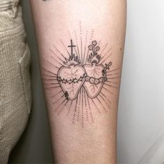 a couple of heart shaped tattoos on the leg with cross and sunburst behind them