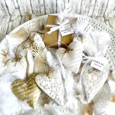 white and gold heart shaped ornaments with tags on them, sitting on a lace doily