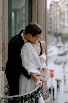 a man and woman standing next to each other in front of a building on a city street