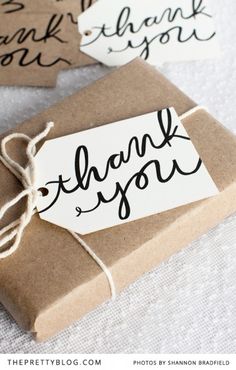 two gift boxes with thank you tags tied to the top, one is brown paper and the other is black ink