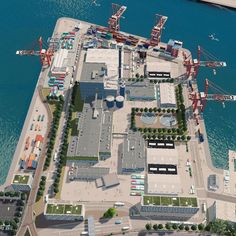 an aerial view of a large industrial area next to the ocean with cranes and buildings