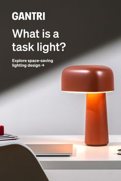 an orange table lamp sitting on top of a white desk next to a laptop computer