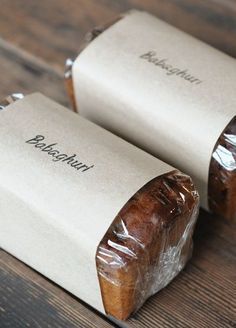 two wrapped breads sitting on top of a wooden table next to eachother