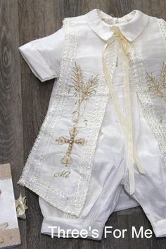 a baby's christ gown and shoes are on the floor next to an envelope