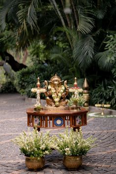 two potted plants sitting on top of a table in the middle of a courtyard