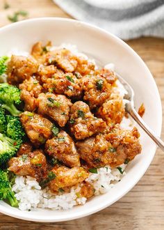 a white bowl filled with rice and meat next to broccoli on a wooden table