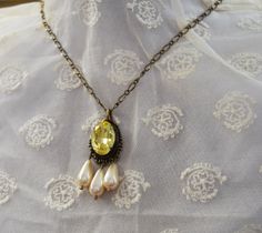 This necklace features an elaborate filigree setting with a large 18mm Aurora Crystal focal stone in a Citrine yellow with three creamy glass pearl dangles. The delicate chain is 18" long. Best for Regency, Victorian, or Edwardian use. Antique Gold finish Note that this can be custom ordered in many colors! Please contact me (taylor@damesalamode.com) for customization options! Victorian Pearl Drop Necklace For Gifts, Victorian Pearl Drop Necklace As Gift, Victorian Style Pearl Drop Necklace As Gift, Victorian Style Pearl Drop Necklace For Gift, Vintage Dangle Pearl Drop Necklace, Vintage Pearl Drop Dangle Necklace, Elegant Yellow Oval Necklace, Yellow Teardrop Necklace For Formal Events, Yellow Teardrop Necklace For Formal Occasions