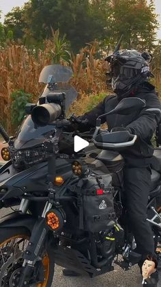 a man riding on the back of a motorcycle down a street next to tall grass