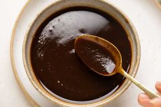 a spoon in a bowl filled with brown liquid