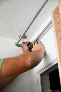 a man is working on the side of a door with two metal bars attached to it