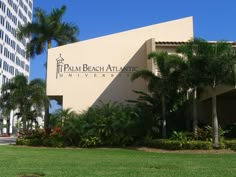 palm beach atlantic university sign on the side of a building with trees and bushes around it