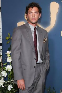 a man in a suit and tie standing next to flowers