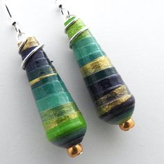 pair of green and gold earrings on white surface with metal ear wires hanging from them