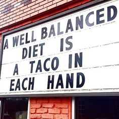 a sign that says a well balanced diet is a taco in each hand on the side of a building