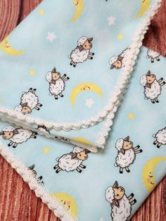 two pieces of cloth with sheeps and stars on them sitting on top of a wooden table