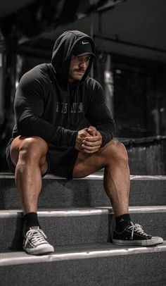 a man sitting on some steps with his hands clasped to his knees and looking at the camera