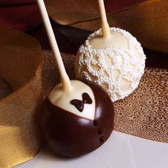 two chocolate covered cake pops with white frosting