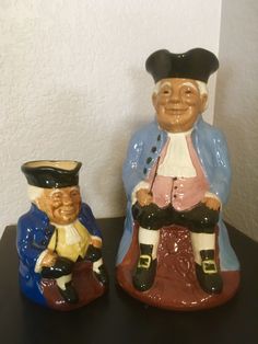 two ceramic figurines sitting next to each other on a table