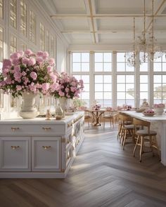 a large kitchen with white cabinets and pink flowers in vases on the counter top