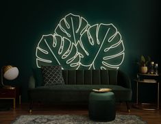 a living room with green walls and a black couch in front of a neon sign