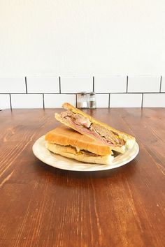 a sandwich on a plate sitting on top of a wooden table