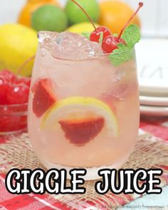 a close up of a drink in a glass on a table with fruit behind it