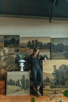 a woman standing in front of some paintings