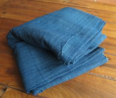 several folded blue jeans on a wooden floor