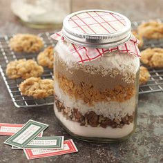 a glass jar filled with food sitting on top of a counter next to some cookies