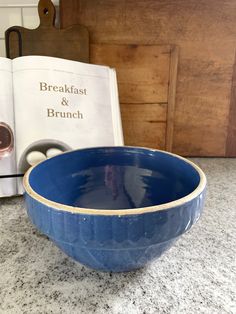 a blue bowl sitting on top of a counter next to an open book