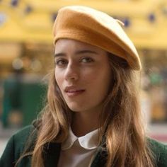 a woman with long hair wearing a green jacket and a brown hat on her head