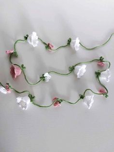 crocheted garland with white and pink flowers hanging from it's sides on a table