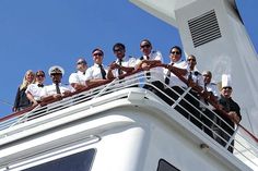 a group of people standing on the side of a boat wearing sailor's uniforms