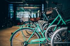 several bicycles are parked in a row outside the building, one is green and the other is blue