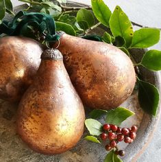 three pomegranates sitting on top of a plate next to leaves and berries