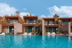 an outdoor swimming pool with lounge chairs next to it and two buildings in the background