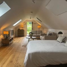 an attic bedroom with white walls and wood floors is furnished with modern furniture, as well as a large bed that sits in the center of the room